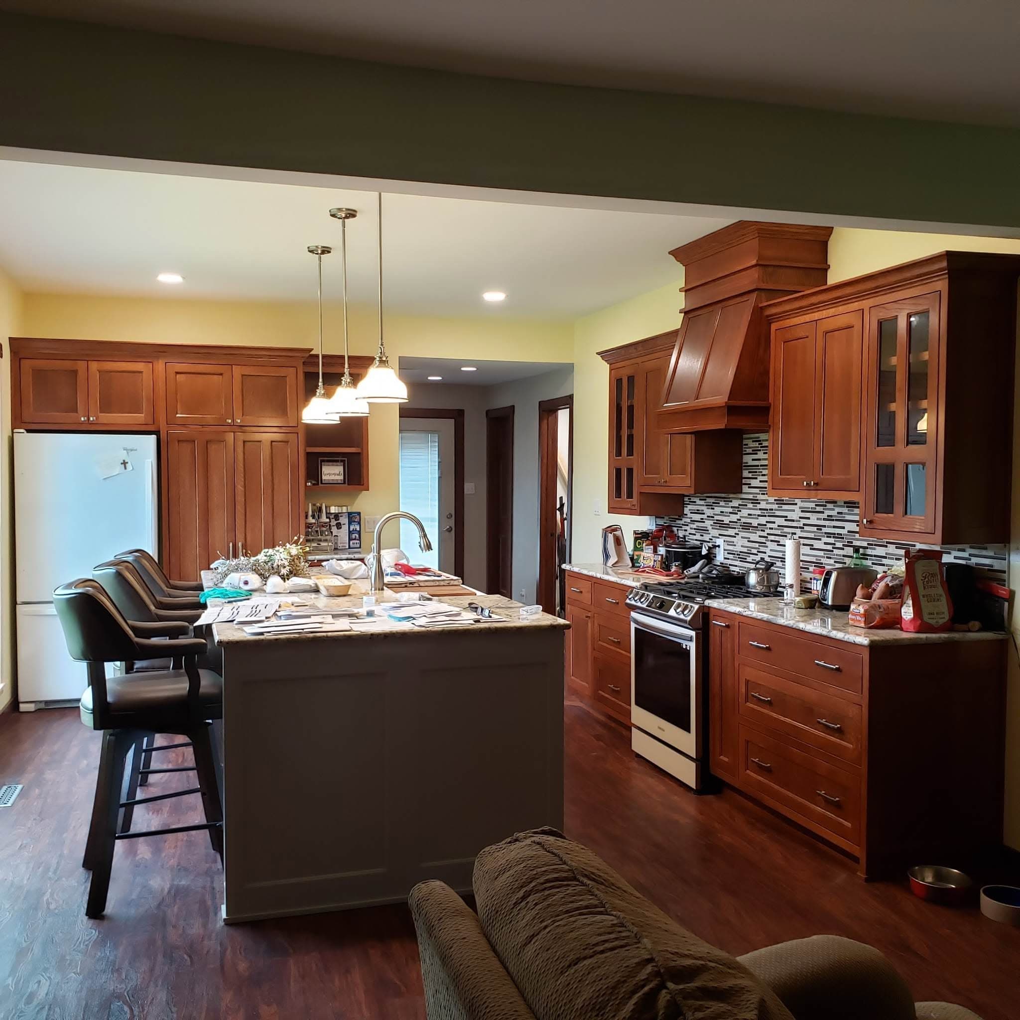 Cherry kitchen cabinetry with mosaic tile backsplash and slide-in range