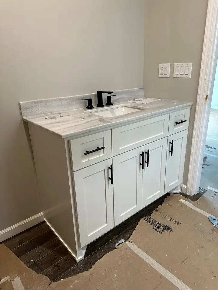 Finished white Shaker bathroom vanity with stone top, inset sink, and matte black fixtures